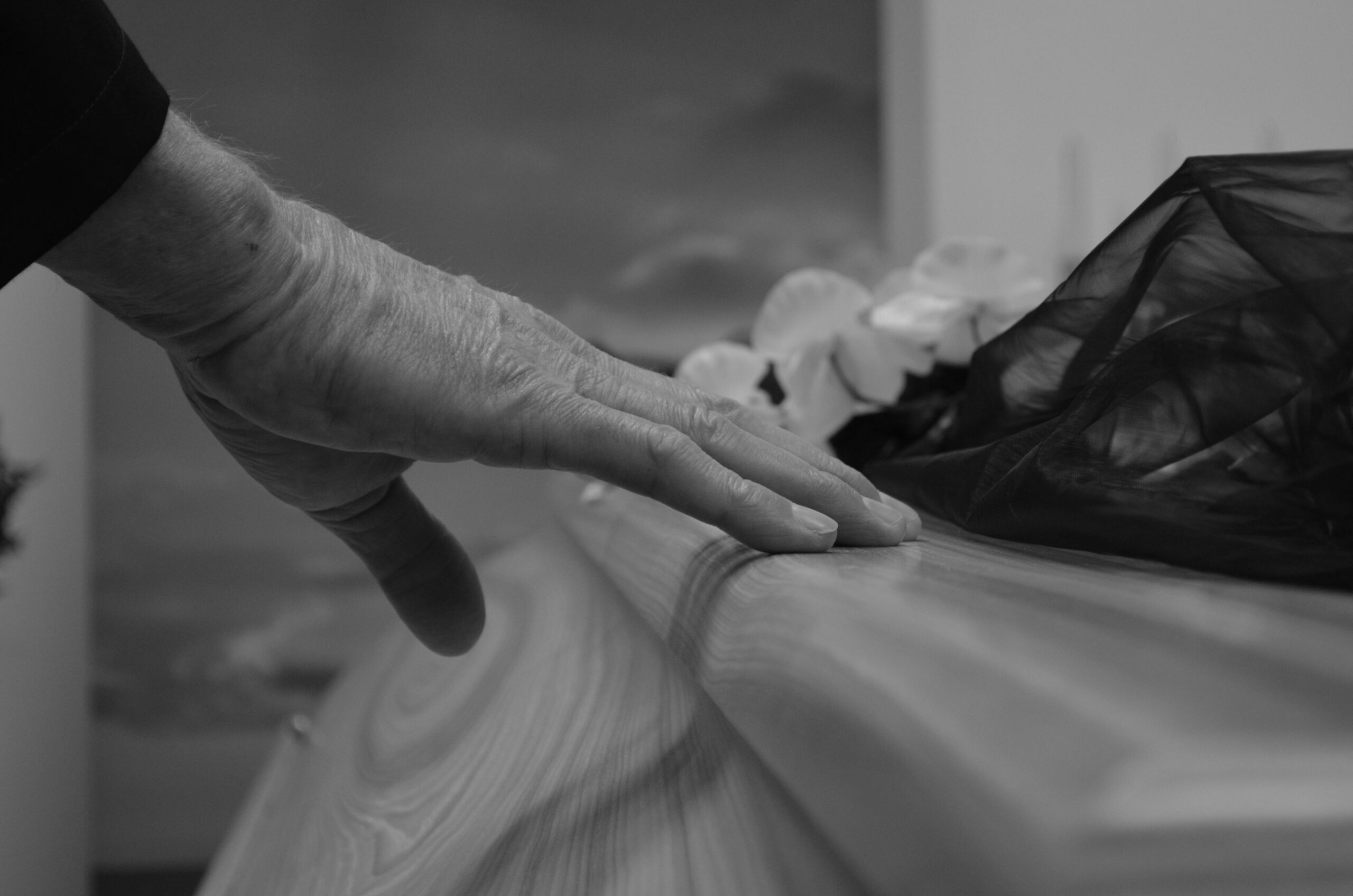 black and white photo of a hand touching a coffin
