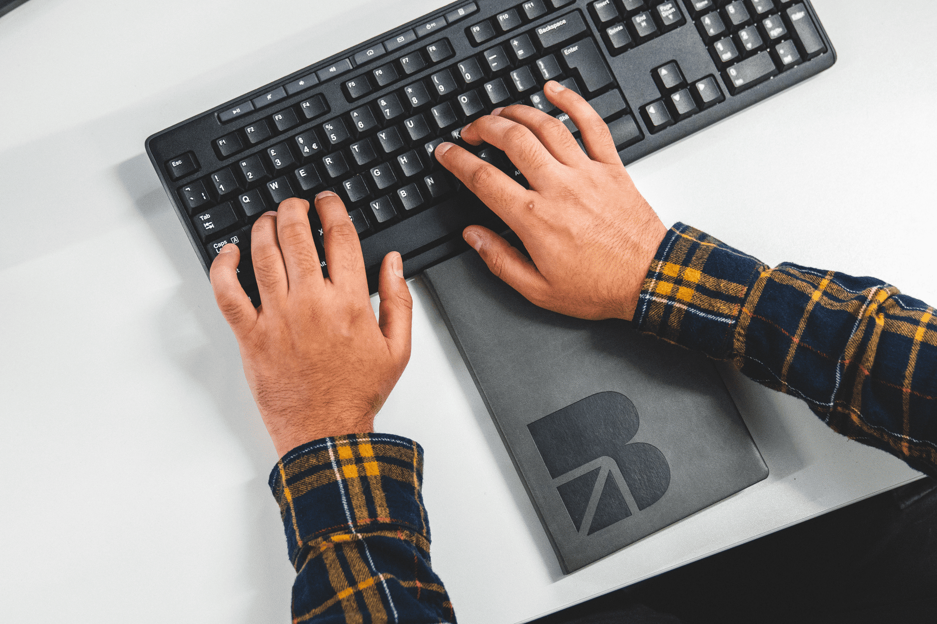 person typing on a keyboard with BAND notebook